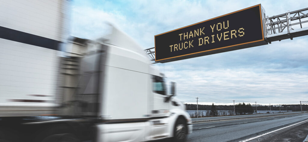 Thank You Truck Drivers on an overhead highway sign during the Coronavirus pandemic, out of focus semi truck in foreground.